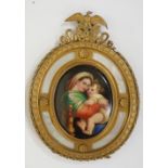 A continental oval porcelain plaque decorated with Madonna and child contained within an ornate