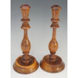 Treen - a pair of yew wood candlesticks with tapered cylindrical nozzles and vasular turned columns,