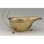 A silver sauce boat of conventional form, three stylised shell and hook feet,