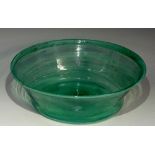 An Arts and Crafts pale green glass bowl, with folded rim, decorated in streaks of white,