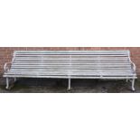 A large slatted garden bench with scrolling ends and supports joined by stretchers, 304cm wide,