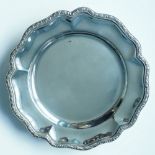 A silver salver, the petal shaped rim with applied scroll border, plain body, four ball feet,