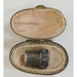 A continental silver coloured metal thimble, the collar set with grey stones,