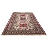 A Caucasian rug with three red and black medallions on cream ground filled with geometric motifs,
