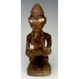 An African carved wooden figure of a female seated form with suckling infant, 17.