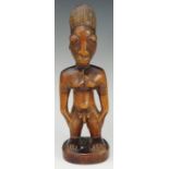 An African tribal figure of a man, standing, his hands on his hips,