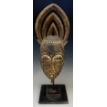 An African tribal mask with ornate carved headdress, mounted on a stand, 56cm high overall,