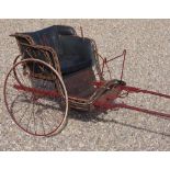 A small two wheeled pony trap, the burgundy painted metal and wooden frame with woven rim,