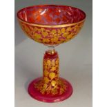 A Moser cranberry coupe glass, the bowl and hollow stem profusely gilded with scrolling foliage,