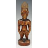 An African tribal figure of a man, standing, his hands on his hips, beadwork necklace,