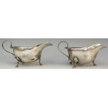 A near pair of silver sauce boats, scroll handles, hoof feet,