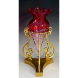 A cranberry glass graduated flute with ruffled rim, with gilded brass stand,