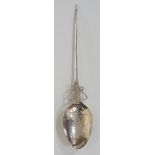 A silver coloured metal spoon, ribbed rim to hammered and floral engraved bowl,