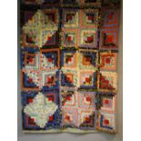 An early to mid 20th Century log cabin patchwork quilt made up of ten by ten multi coloured squares,