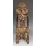 An African tribal seated figure, the face with dished eyes and wide mouth,