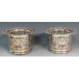 A pair of silver plated bottle coasters, the bodies pierced with scrolls, bars and crosslets,