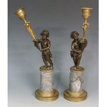 A pair of Regency bronze candlesticks modelled as infants holding cornucopias candle brackets,