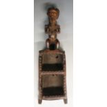 A tribal carved shelf or box surmounted by a female figure,