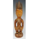 An African tribal figure of a female, with hands on her hips, ornate hair,