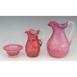 A Victorian cranberry flashed glass jugs, both the body and applied clear handle spirally moulded,