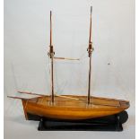 A late 19th / early 20th Century two masted wooden hulled model boat on a black painted stand,