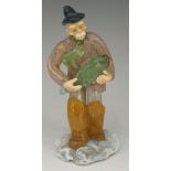 An art glass sculpture of a fisherman in waders, walking through surf holding a fish,