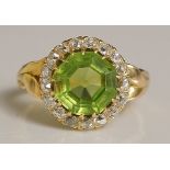 A peridot and diamond ring the central cut peridot surrounded by a border of circular diamond