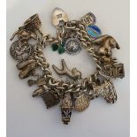 A silver curb link charm bracelet hung 24 charms,