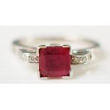 A 14ct white gold ruby and diamond ring the cushion cut ruby in scrolling diamond set shoulders,