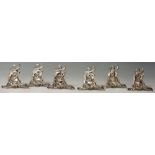 A set of six Continental silver menu holders in the form of cherubs holding champagne bottles and