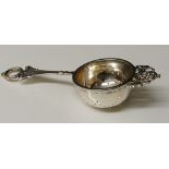 Paul Storr - a silver tea strainer, the handle with wreath finial above diamond hatched handle,