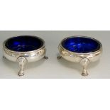 A pair of George II cauldron form salts with blue glass liners, stepped hoof feet,