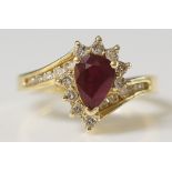 A 14ct yellow gold crossover ruby and diamond ring the pear shaped ruby flanked by small diamond