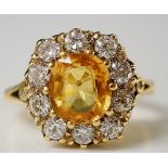 An 18ct yellow gold yellow sapphire and diamond ring the claw cut oval yellow sapphire surrounded