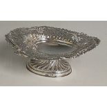 A silver heart shaped pedestal dish, the pierced sides chased and embossed with scroll and foliage,