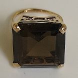 A 9ct gold smoky quartz dress ring the claw set cushion cut stone in deep pierced frame,