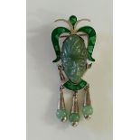 A Mexican silver pendant/brooch set with a carved green hardstone face flanked by malachite scrolls