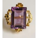 A 14ct yellow gold amethyst ring the claw set baguette cut stone in a rectangular textured collet