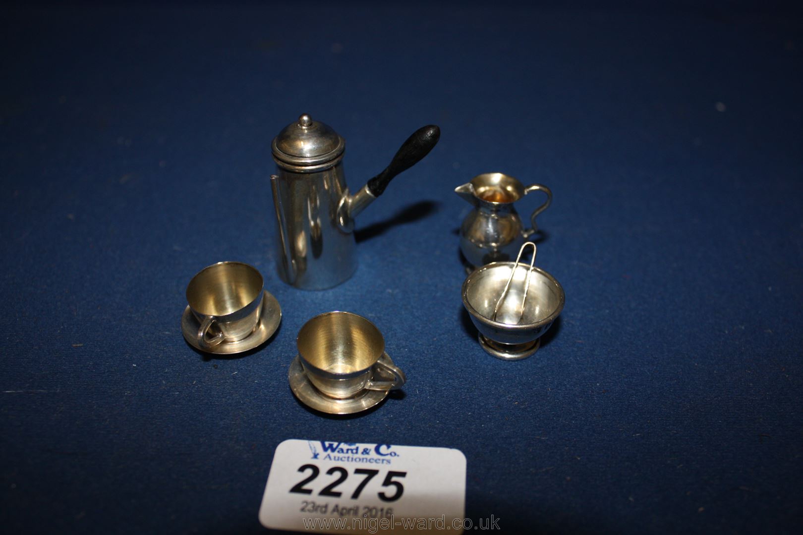 A miniature Silver Coffee Pot, two cups and saucers, cream jug, sugar bowl and tongs.