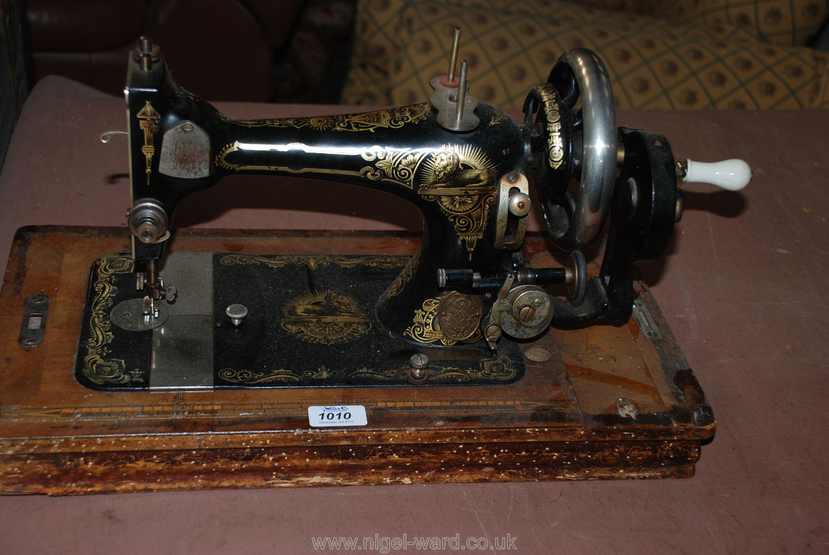 An old hand Sewing Machine with attachments, no cover.