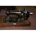 An old hand Sewing Machine with attachments, no cover.