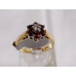 9CT DAISY CLUSTER RING. 9ct gold garnet and daisy cluster ring, size K