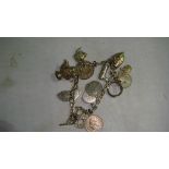 Silver charm bracelet with assorted silver and base metal charms including coins, pistol, iron,