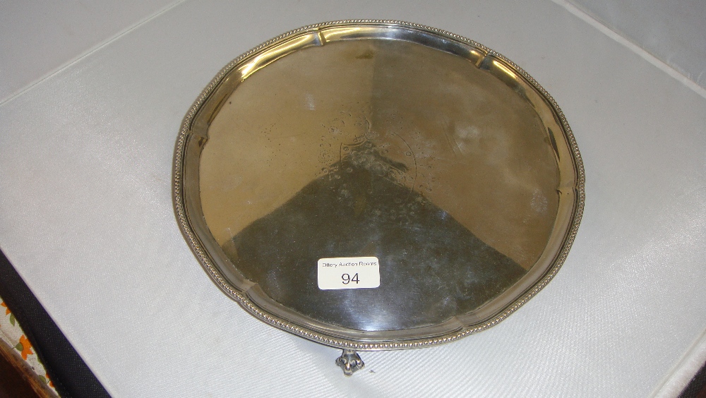 Solid silver salver of circular form with beaded edge on three ball and claw feet with armorial