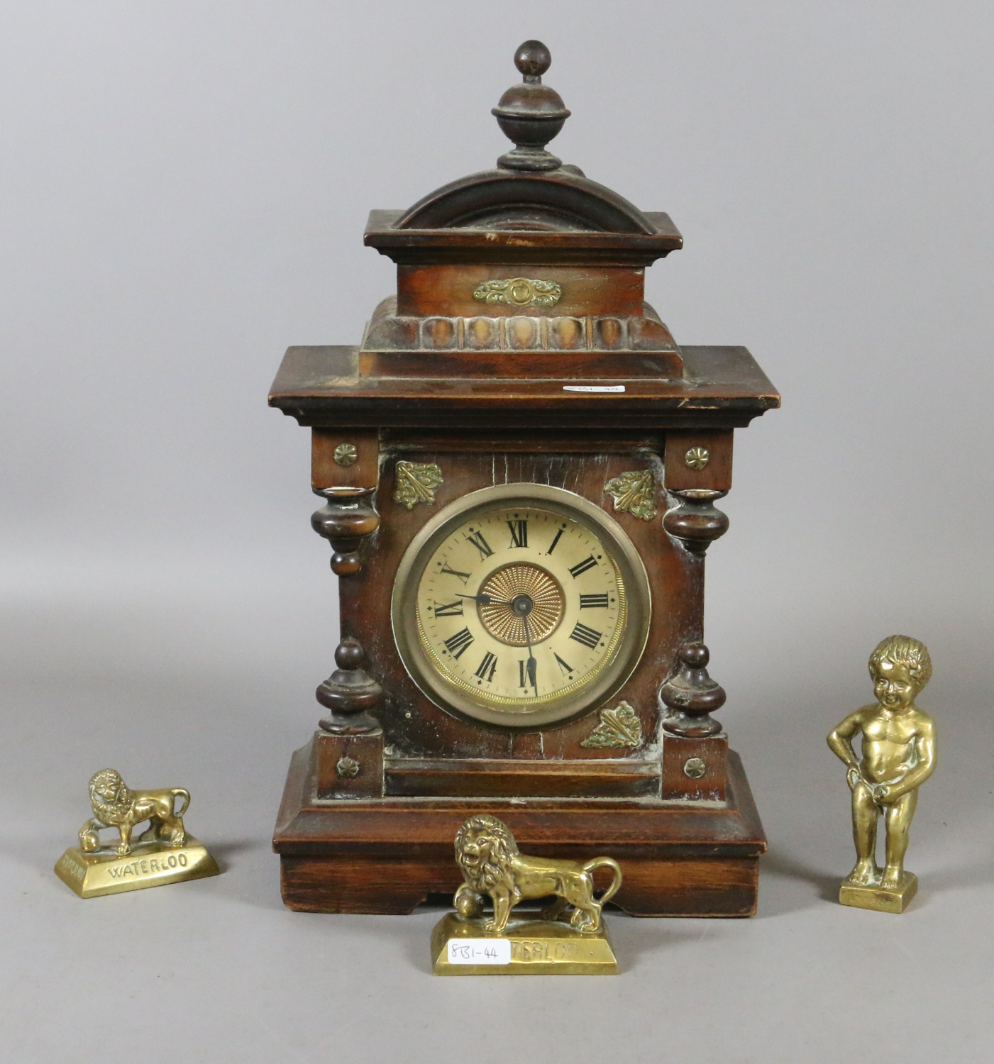A continental carved and turned mahogany musical alarm clock and three brass ornaments.