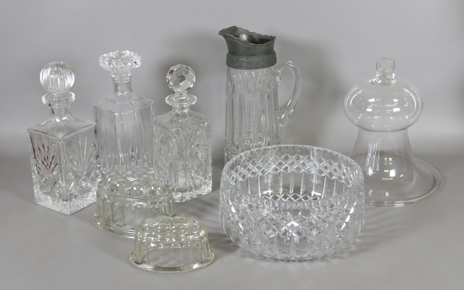 A collection of cut glass items including decanters, a jug and a glass smoke bell.