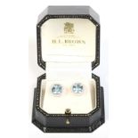 A pair of 18 carat white gold earrings set with square cut aquamarines under borders of brilliant
