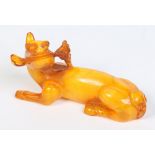 A Chinese carved amber model of a recumbent beast holding a ruyi branch in its mouth, 14cm.