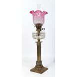 A Victorian brass based oil lamp with clear glass font and quilted cranberry glass shade.