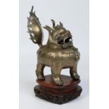 A 19th century Chinese bronze censor formed as a Kirin and raised on a carved and pierced hardwood